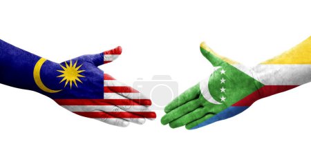 Photo for Handshake between Comoros and Malaysia flags painted on hands, isolated transparent image. - Royalty Free Image