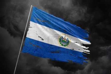 El Salvador torn flag on dark sky background.