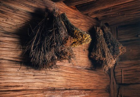 Photo for A bouquet of dried wild herbs and flowers hanging on a wooden wall in sauna. - Royalty Free Image
