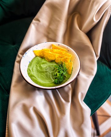 Photo for Homemade broccoli cream soup in white bowl with chips - Royalty Free Image