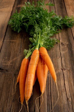 Verduras frescas del concepto de mercado semanal: vida sana y compras. Ramo de zanahorias frescas del mercado semanal sobre un fondo rústico de madera.
