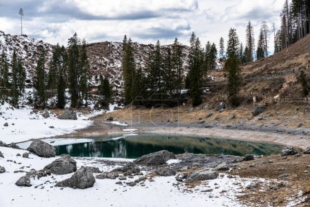 Téléchargez les photos : La légendaire sirène d'eau est assise sur un rocher à côté du Karersee cristallin, vert-bleu et beau, entouré de forêts et de montagnes - en image libre de droit