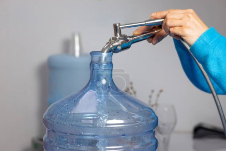 Téléchargez les photos : Fermer les mains de femmes remplissant un gallon d'eau propre avec un robinet. Photo de haute qualité - en image libre de droit