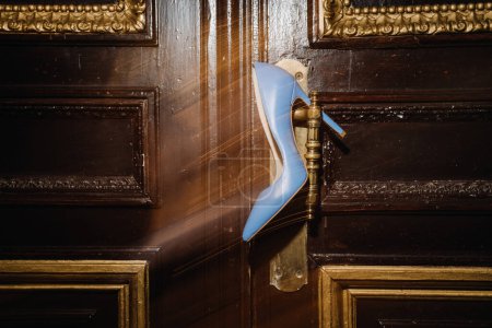 Photo for A stylish blue high heel shoe positioned on a vintage gold door handle, blending classic and contemporary elements for a timeless, sophisticated look - Royalty Free Image