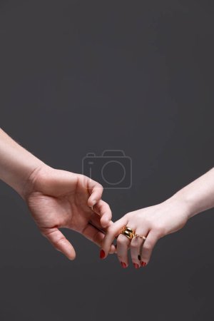 This image captures a tender moment of two hands, adorned with elegant rings, reaching out to each other against a contrasting dark background. Its a symbol of unity, connection, and love