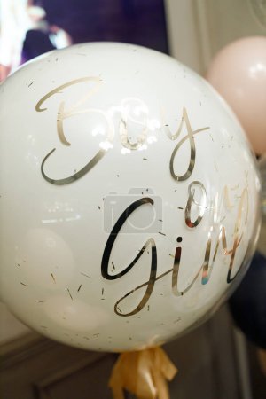Photo for A close-up view of a white balloon adorned with golden speckles and the handwritten text Boy or Girl, symbolizing the anticipation and excitement of unveiling a babys gender at a reveal party - Royalty Free Image