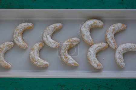 Téléchargez les photos : Vanillekipferl biscuits de cuisson de Noël typiques tchèque doux, rouleaux de vanille croissant de lune avec glaçage blanc sur une longue assiette en rangées - en image libre de droit