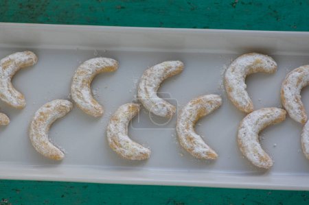 Téléchargez les photos : Vanillekipferl biscuits de cuisson de Noël typiques tchèque doux, rouleaux de vanille croissant de lune avec glaçage blanc sur une longue assiette en rangées - en image libre de droit