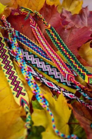 Photo for Handmade homemade colorful natural woven bracelets of friendship isolated on autumnal natural leaves background, beautiful bright colors - Royalty Free Image