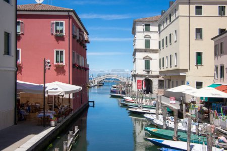 Téléchargez les photos : Chioggia, ITALY - June 8, 2022: Pictoresque streets of Chioggia town with water canal, boats and old buldings in sunlight - en image libre de droit