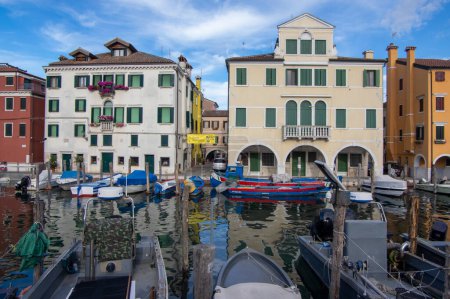 Foto de Chioggia, ITALIA - 8 de junio de 2022: Camino de la vida en la ciudad italiana Chioggia con canal de agua y barcos en el cielo azul claro - Imagen libre de derechos