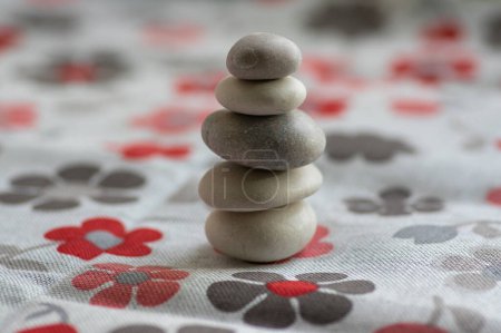 Téléchargez les photos : Cairn de pierre sur fond blanc avec des étoiles de fleurs rouges et grises, tour de cinq pierres, pierres d'équilibre simples, harmonie et équilibre de simplicité, rock zen - en image libre de droit