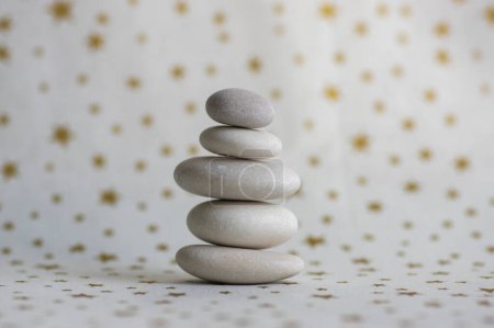 Photo for Stone cairn on white background with golden stars, five stones tower, simple poise stones, simplicity harmony and balance, rock zen - Royalty Free Image