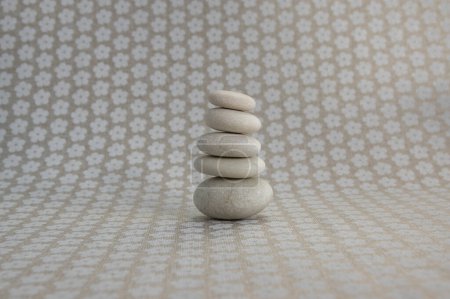 Photo for Stone cairn on gray background with white flowers stars, five stones tower, simple poise stones, simplicity harmony and balance, rock zen - Royalty Free Image
