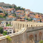 Kavala, Greece - June 13, 2023: Byzantine aqueduct Kamares from 16th century a landmark of the city on Aegean Sea, Houses of old town in background. 