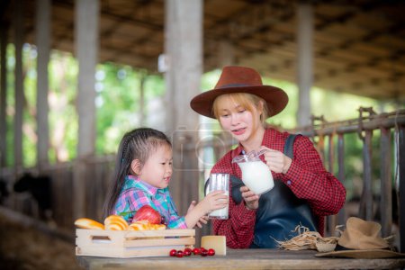 Téléchargez les photos : Jeune femme et enfants qui boivent du lait frais dans une exploitation laitière - en image libre de droit