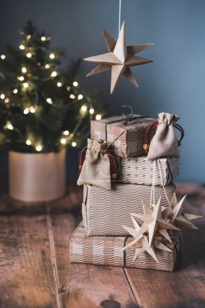 Téléchargez les photos : Cadeaux de Noël, petit sac en coton, étoiles, huttes de glands sur fond bois près du sapin de Noël. . Photo de haute qualité - en image libre de droit