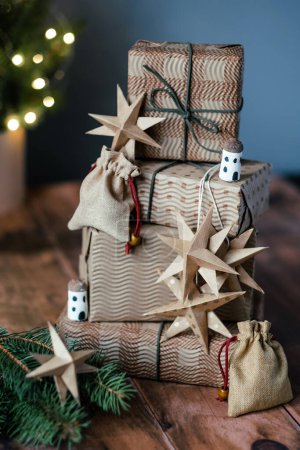 Téléchargez les photos : Cadeaux de Noël, petit sac en coton, étoiles, huttes de glands sur fond en bois près du sapin de Noël. - en image libre de droit