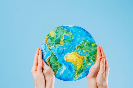 Photo for Mother and son hold a picture of the Earth on a blue background. Save the planet. The concept of environmental protection and energy saving. High quality photo - Royalty Free Image