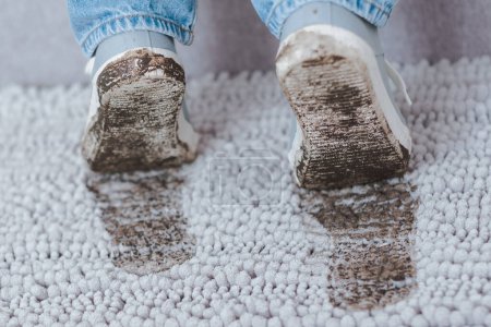 Téléchargez les photos : Empreinte boueuse sur tapis gris. Chaussures sales avec boue et terre. La vie quotidienne sale tache. Photo de haute qualité - en image libre de droit