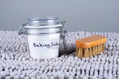 Photo for Baking soda and wooden cleaning brush on a gray carpet at home. The concept ecological cleaning and disinfection. High quality photo - Royalty Free Image