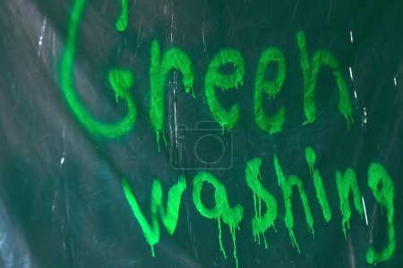 Téléchargez les photos : Graffiti Graffiti Greenwashing pulvérisé avec de la peinture verte sur le polythène. Commercialisation trompeuse d'un produit écologique, de services ou d'une entreprise, de marques. Photo de haute qualité - en image libre de droit