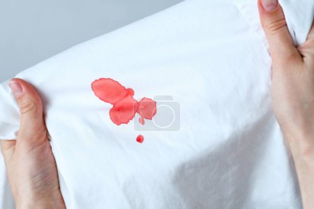 Close up drops stain of blood on a white cloth. Spoiled clothes. Dirty stain for cleaning concept. High quality photo