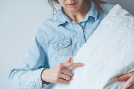 Mujer sin rostro señalando chinches en una almohada blanca. Problemas de salud y trastornos del sueño. Foto de alta calidad