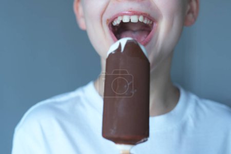 Foto de Cerrar niño mordiendo helado de chocolate. Dulce desierto. Concepto de salud dental. Foto de alta calidad - Imagen libre de derechos