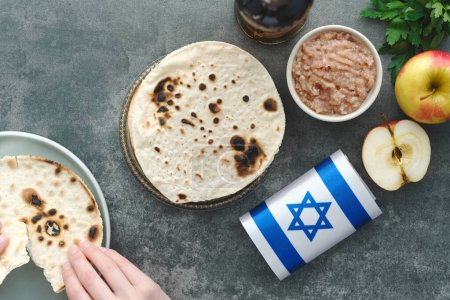 Female hands holding handmade round Matzah in a plate on a concrete background. Saved Jewish Pesach Tradition. Jewish Passover celebrations. top view. High quality photo