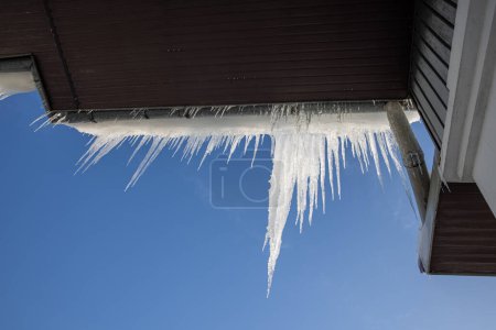 Foto de Icicles que cuelgan del techo de la casa. Cálido día de invierno - Imagen libre de derechos