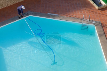 Foto de Hombre limpiando la piscina con equipo de vacío. limpieza de la piscina. Un hombre está limpiando la piscina. atención de servicio. - Imagen libre de derechos