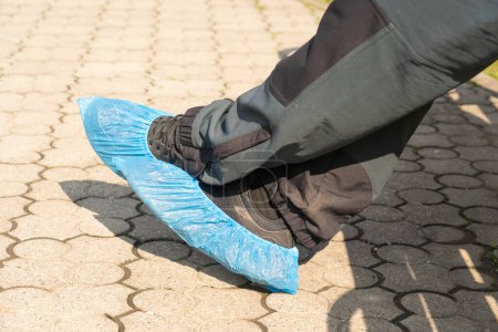 Photo for Close-up of person feet wearing shoe-covers for protection outside in park - Royalty Free Image