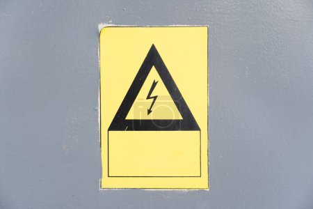 Foto de Close-up of warning yellow sign for electricity isolated on grey background - Imagen libre de derechos
