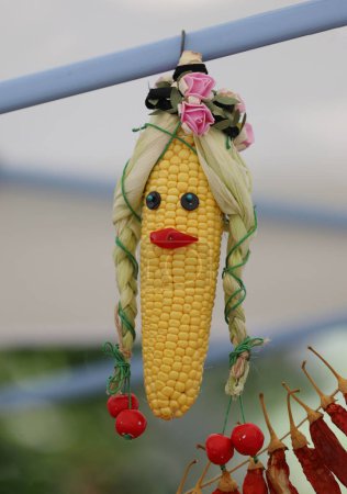 Téléchargez les photos : Concept d'automne avec drôle de poupée de maïs suspendue devant le marché saisonnier, plan extérieur - en image libre de droit