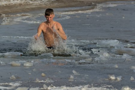 Foto de Kiev, Ucrania - 19 de enero de 2022: Hombre sumergido en agua helada en el día de invierno. Ritual tradicional de bautismo. La fiesta Epifanía en el helado río Dnipro. - Imagen libre de derechos