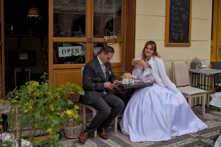 Foto de Praga, República Checa - 8 de octubre de 2023: Los recién casados desconocidos se sientan a la mesa en un café callejero en Praga. Impresionante naturaleza, exquisita arquitectura y vibrante vida de la antigua ciudad. - Imagen libre de derechos