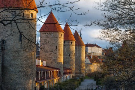 Photo for A view of the wall with guard towers in the evening light of the sun. Stenbock's house from afar. A colorful picture of the evening Tallinn. Medieval architecture of the country. Spring season. - Royalty Free Image