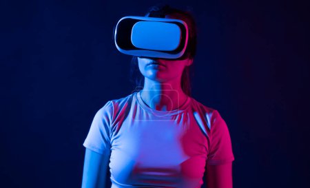 Téléchargez les photos : Femme brune utilisant des lunettes de réalité virtuelle à l'intérieur. Fille s'amuser avec innové vr googles technologie - en image libre de droit