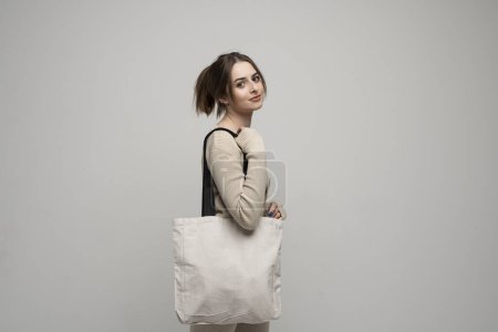 Photo for Brunette young girl holding linen shopping bag, mock up. Lady holding flax shopper handbag. Fashion and ecology concept - Royalty Free Image