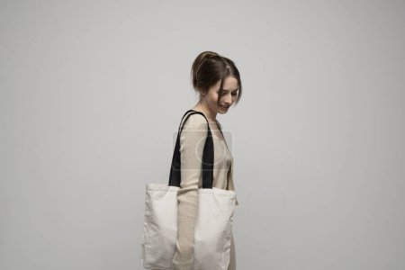 Photo for Happy brunette young girl holding linen shopping bag, mock up. Lady holding flax shopper handbag. Fashion and ecology concept - Royalty Free Image