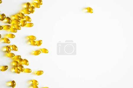 Téléchargez les photos : Fermer les capsules de vitamine D3 softgel sur une surface blanche. Softgels jaunes, vue du dessus, espace de copie. Compléments alimentaires. Concept de soins de santé et de soutien immunitaire - en image libre de droit