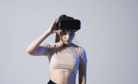 Téléchargez les photos : Portrait of young brunette woman gamer with virtual reality headset on a head - en image libre de droit