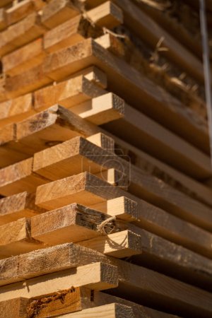 Téléchargez les photos : Des planches de bois empilées en gros plan dans un entrepôt de bois extérieur. Contexte des conseils d'administration. Industrie du bois - en image libre de droit