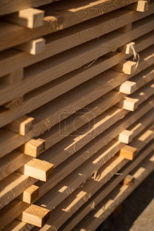 Téléchargez les photos : Planches et poutres en bois dans un entrepôt de bois extérieur dans une industrie du bois. Empilés avec du bois de pin. Panneau bordé plié. Atelier de récolte du bois - en image libre de droit