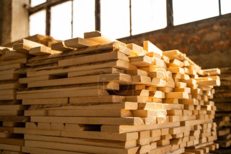 Téléchargez les photos : Empilement de planches de bois brut dans un entrepôt de bois d'oeuvre intérieur. Contexte des conseils d'administration. Séchage du bois brut dans l'entrepôt de bois. Industrie du bois - en image libre de droit