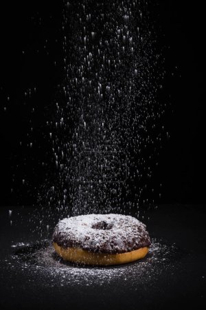 Photo for Sprinkling sugar powder on delicious donut topped with chocolate - Royalty Free Image