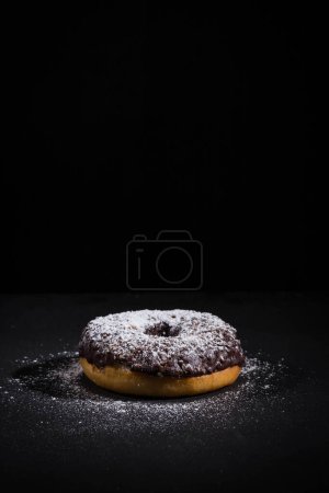 Photo for Sprinkling sugar powder on delicious donut topped with chocolate - Royalty Free Image