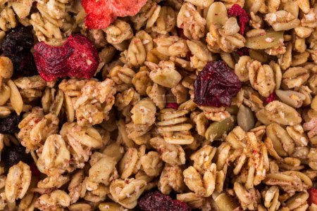 Muesli cereals close up background with  raisins, oat and wheat flakes, fruits, strawberry, cranberry, cherry pieces