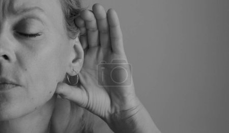 Foto de Mujer que sufre sordera y pérdida de audición sobre fondo gris - Imagen libre de derechos